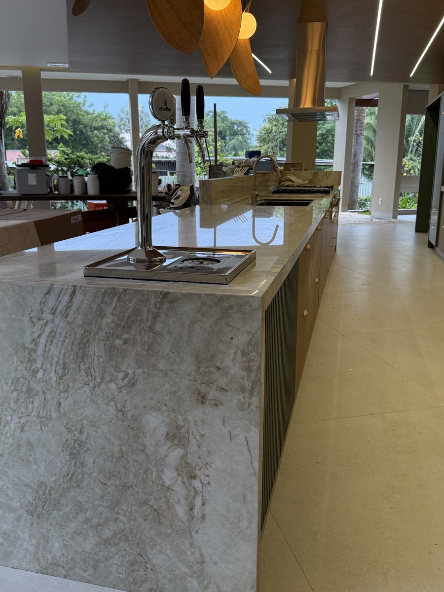Bancada de área gourmet com chopeira embutida em pedra natural