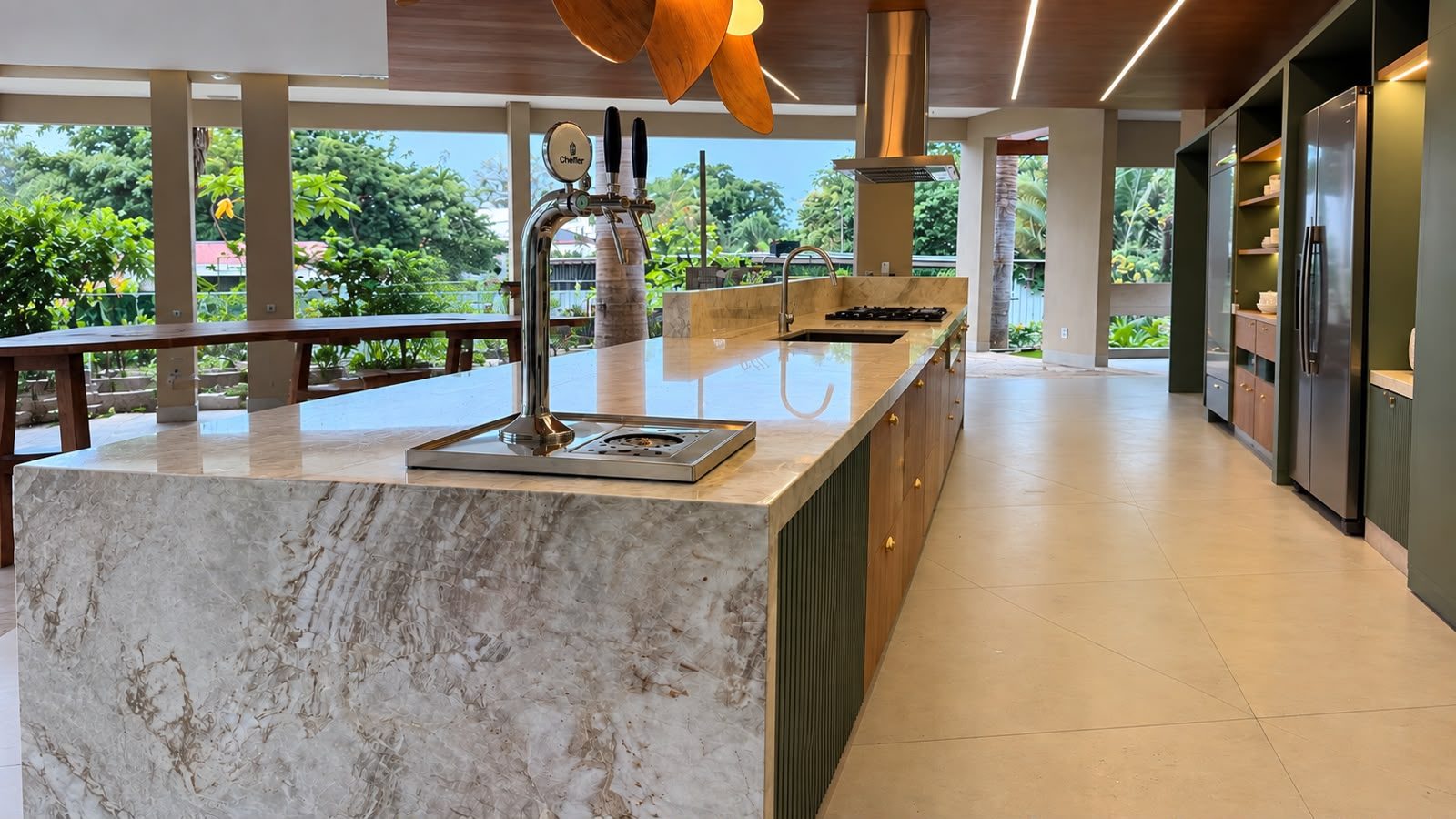 Ilha gourmet em quartzito Taj Mahal com acabamento em meia-esquadria, chopeira e cooktop
